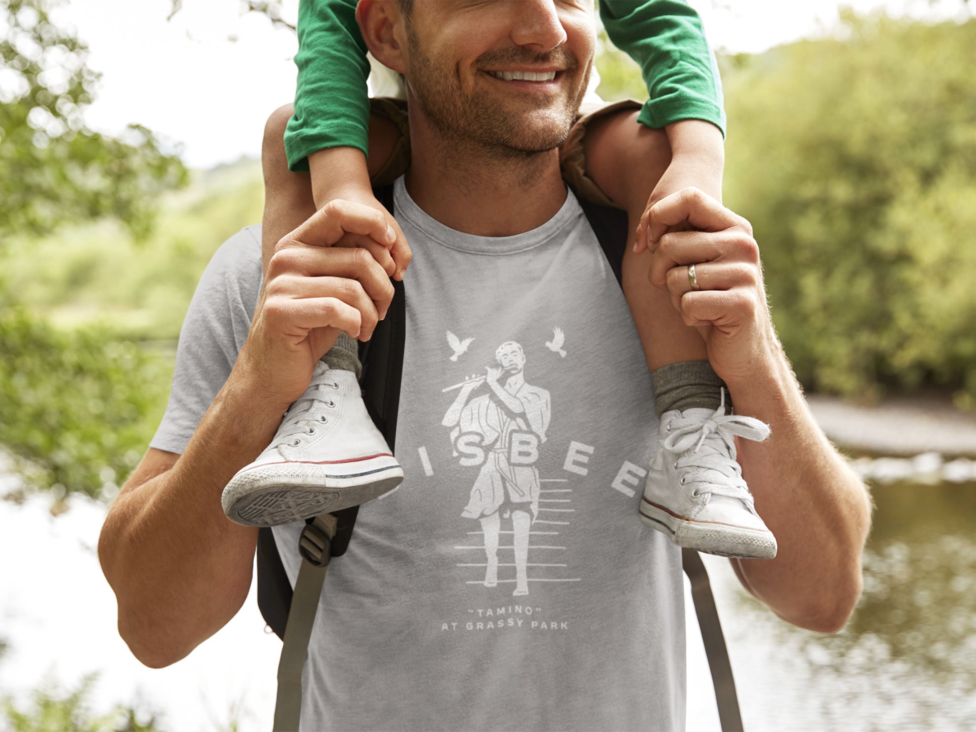 Man in a Bisbee t-shirt carrying a child on his shoulders 
